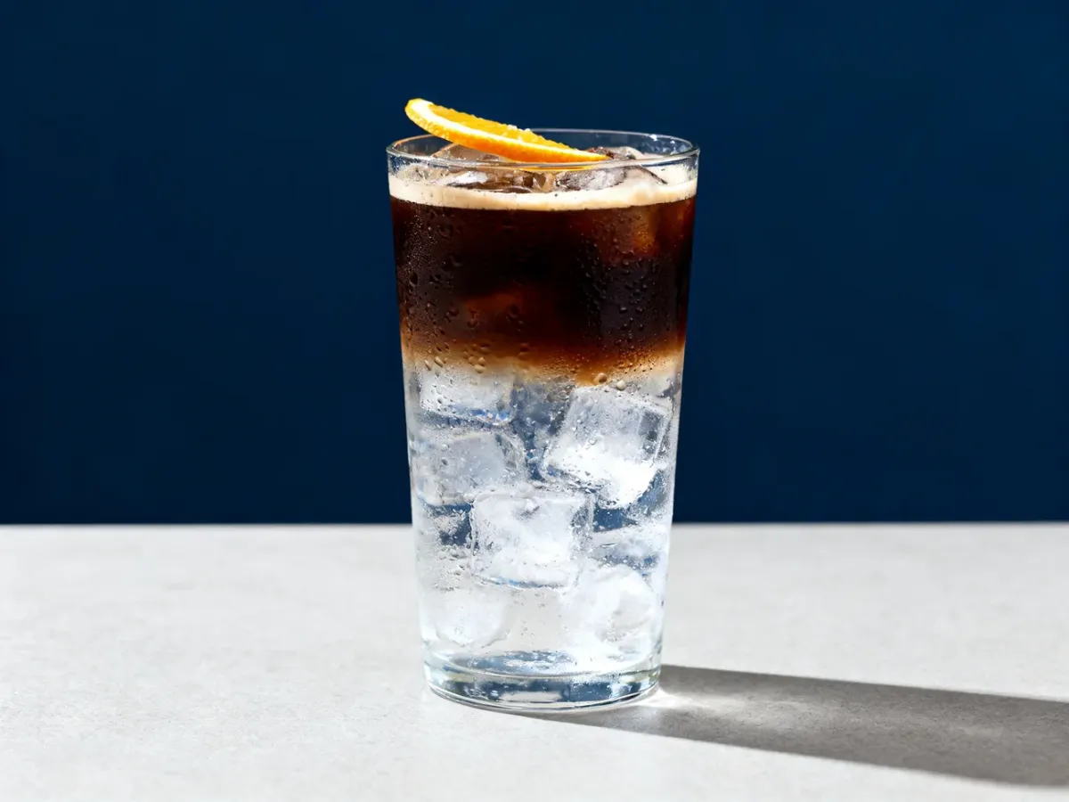 Warstwowe espresso tonic z lodem i plasterkiem cytrusa w wysokiej szklance